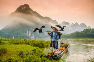 Pescador tradicional chino con cormoranes en una balsa de bambú en el río Li, cerca de las montañas de Yangshuo
